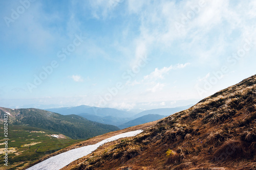 Melting snow on the slopes and hills in spring mountains on sunny day. Carpathian Mountains, Ukraine