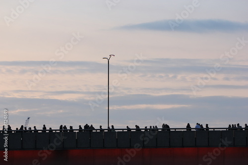 a silhuoette of commuters crossing the London Bridge