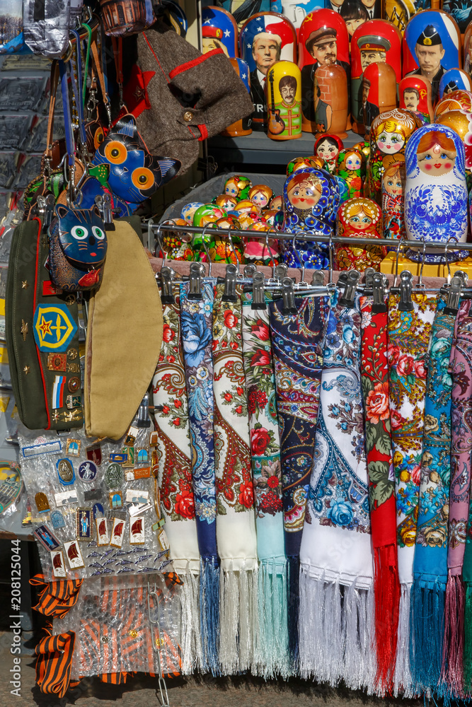 Russian souvenirs such as colorful shawls, scarves, painted matryoshkas, decorative small bags, purses and military headgear lie on the counter and wait for foreign tourists