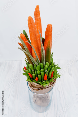 An original vegetable bouquet consisting of carrots, pea pods, lettuce leaves, red pepper and aloe is stand in a glass vase as a symbol of a healthy eating