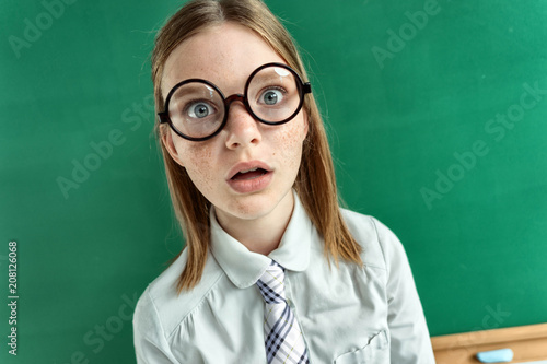 Astonished pupil staring at you with her mouth open / photo of teen school girl wearing glasses, creative concept with Back to school