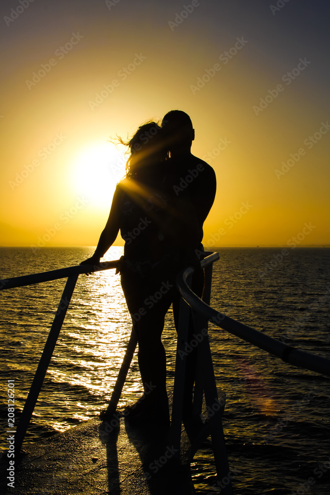 Silhouette of young couple on yacht over sea sunset. Romantic and Love concept.
