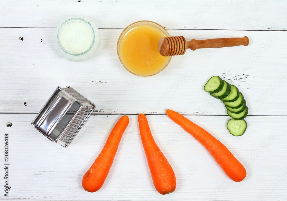 Face mask from carrot, yogurt, honey, top view / Ingredients for facial mask on the white wooden board Face mask from carrot, yogurt, honey, top view / Ingredients for facial mask on the white wooden board