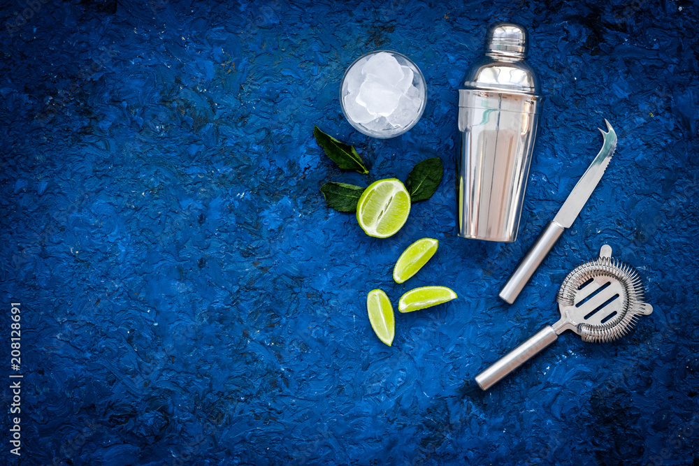 Process of making mojito concept. Ingredients and crockery. Slices of lime, mint, glass with ice cubes, shaker, strainer on blue background top view copy space Process of making mojito concept. Ingredients and crockery. Slices of lime, mint, glass with ice cubes, shaker, strainer on blue background top view copy space