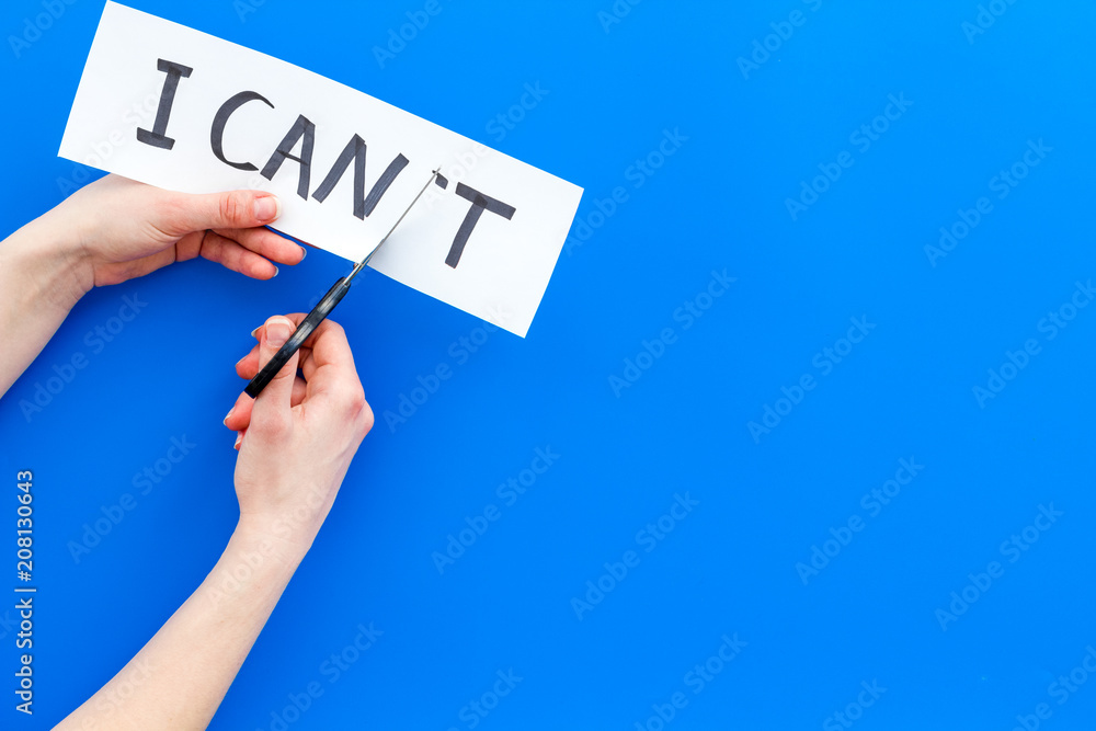 I can concept. Motivate youself, believe in yourself. Hand cut off the letter t of written word I can't by sciccors. Blue background top view copy space I can concept. Motivate youself, believe in yourself. Hand cut off the letter t of written word I can't by sciccors. Blue background top view copy space