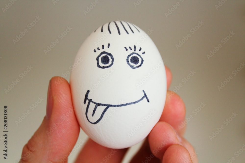 Chicken egg with a painted face in a man's hand. Close-up. Chicken egg with a painted face in a man's hand. Close-up.