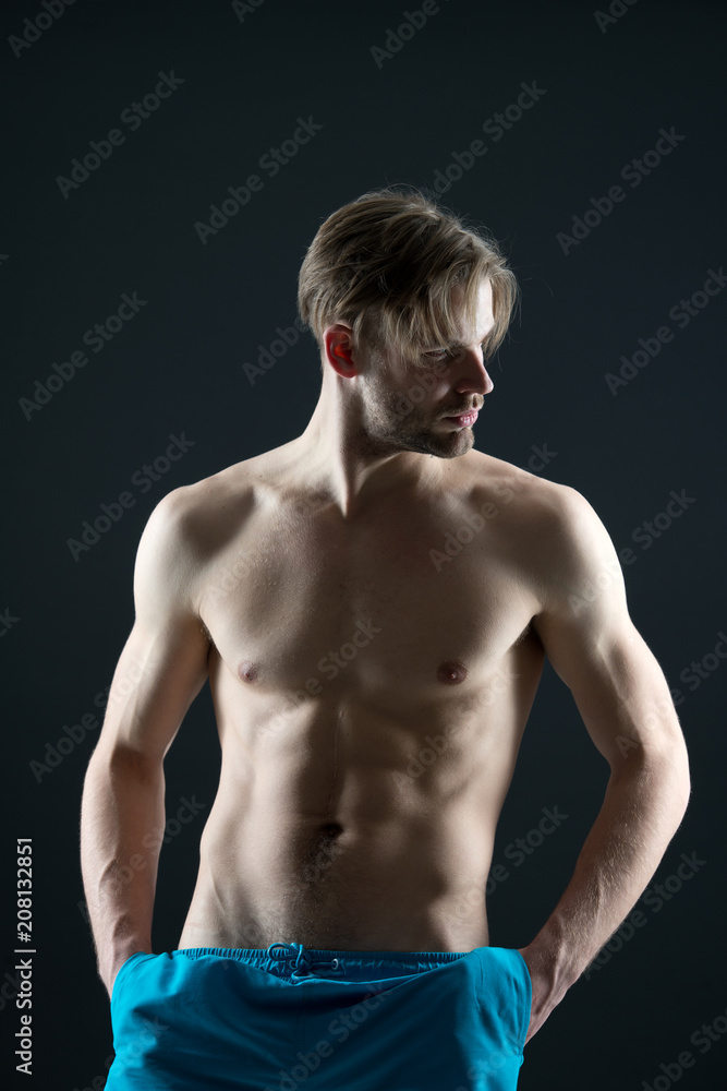 Fototapeta premium Athlete with fit body in shorts. Training and workout activity in gym. Man with six pack and ab muscles. Sportsman with sexy torso and chest. Sport or fitness and bodycare concept