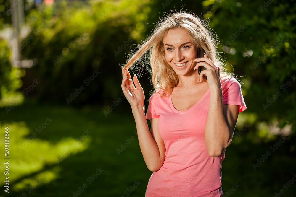 Joyful girl talking on the phone in the Park, sun