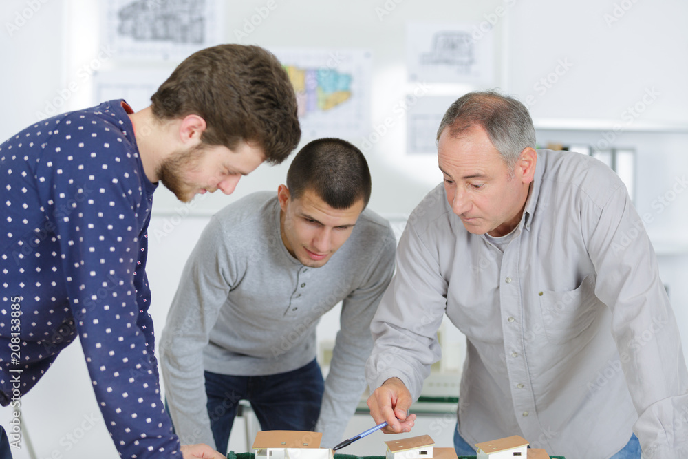 Obraz premium students and teacher bending over scale model