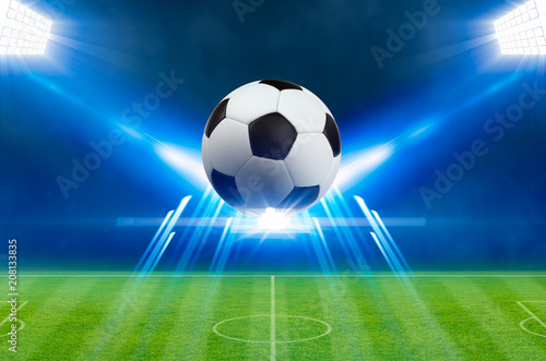 Soccer ball  bright spotlights  illuminates green soccer stadium