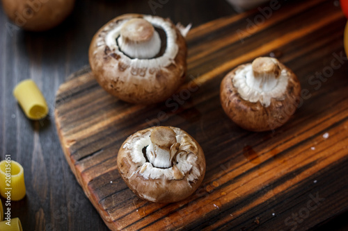 Raw mushrooms on wooden board. Three mushrooms on kitchen.