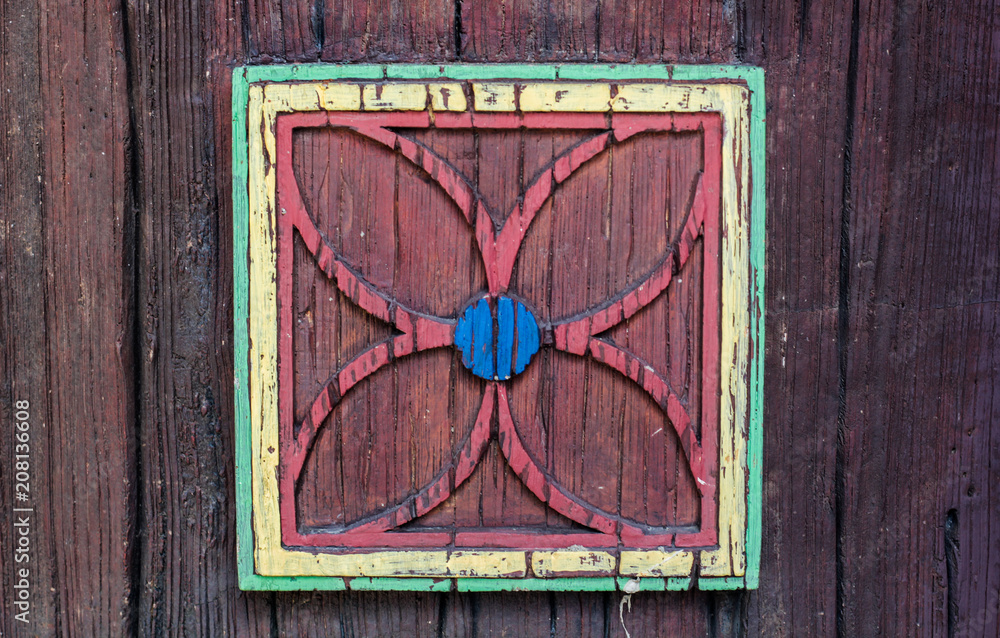 wooden background, applique of a flower in a square of wood, red-green, blue middle