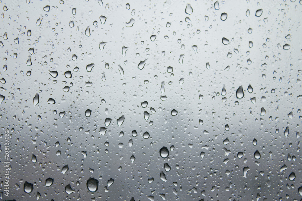 Depression and dreary sad weather shown as water droplets on a window.