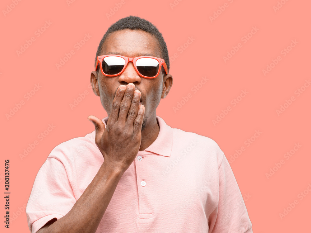 African black man wearing sunglasses covers mouth in shock, looks shy, expressing silence and mistake concepts, scared African black man wearing sunglasses covers mouth in shock, looks shy, expressing silence and mistake concepts, scared