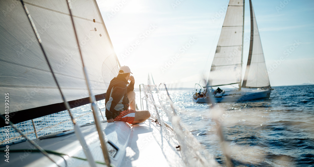 Fototapeta premium Young handsome man relaxing on his sailboat