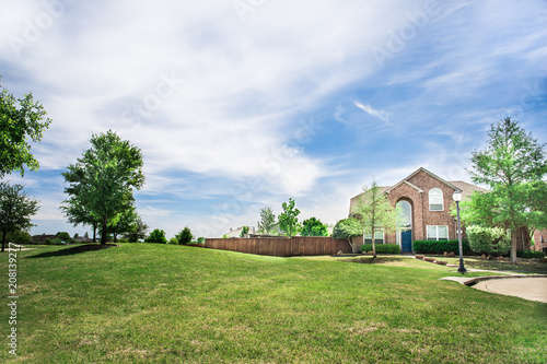 New brick home framed by cloudy blue skies on sunny day © charlfolscher