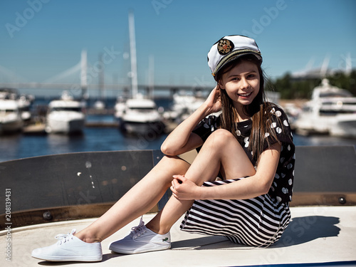 rich beautiful kids on white big yacht in nice weather on blue sea. On the background of the bridge and white sailing yachts © Pavel