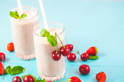 two glasses of smoothies made from milk  strawberries  banana  cherries  decorated with mint on bright pink blue background Concept healthy lifestyle  diet  tasty Copy space