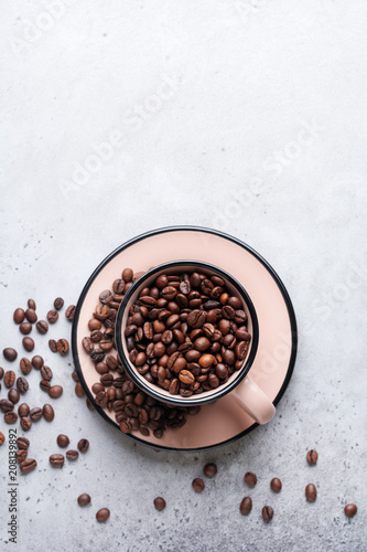 Cup with coffee beans inside on gray concrete background. Top view.