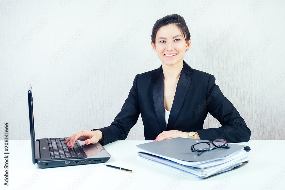 attractive brunette businesswoman in a stylish business suit working in the office with a laptop. concept of business and economics attractive brunette businesswoman in a stylish business suit working in the office with a laptop. concept of business and economics