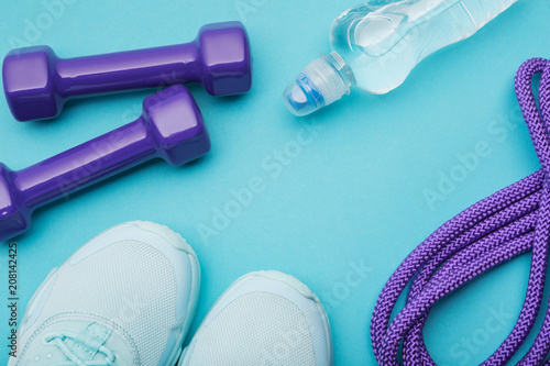 turquoise sneakers, a bottle of water, lilac dumbbells and a skipping rope on a turquoise background, minimalism, concept fitness and water