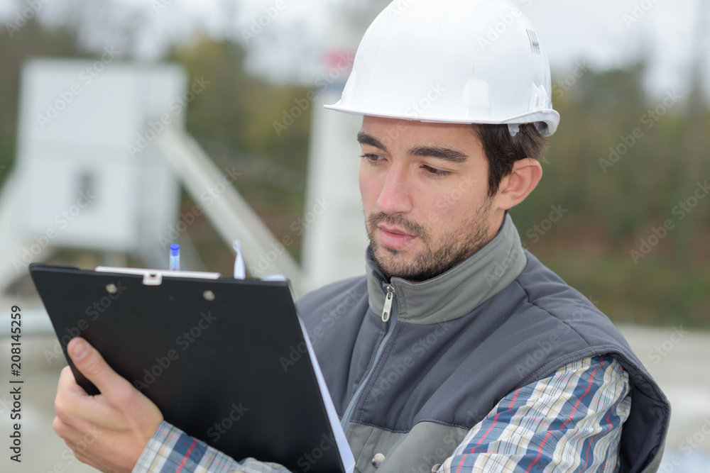 male architect with blueprints reading clipboard outdoors male architect with blueprints reading clipboard outdoors