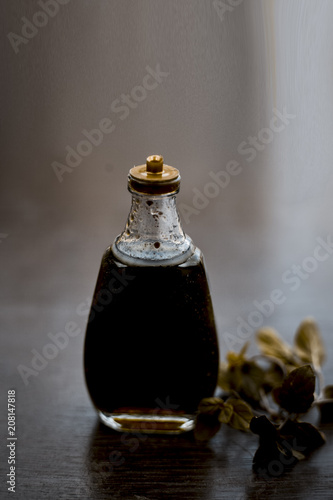 Ayurevedic essence or oil of holy basil or tulsi in a transparent bottle with some fresh bright basil leaves on wooden surface used in many treatments and home remedies related to cough, and fever. photo