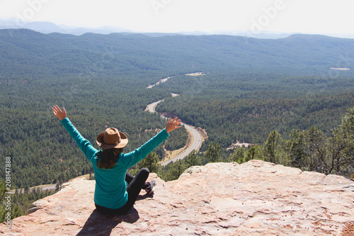 Young woman with hat looking down the road and open her arms to feel freedom