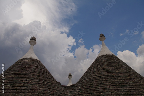 Alberobello Puglia trulli pinnacoli antico tetto pietra cielo azzurro nuvola