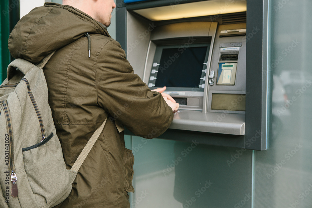 The tourist withdraws money from the ATM for further travel. Finance, credit card, withdrawal of money. The tourist withdraws money from the ATM for further travel. Finance, credit card, withdrawal of money.