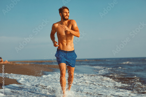 Handsome young man having fun on the beach by the sea