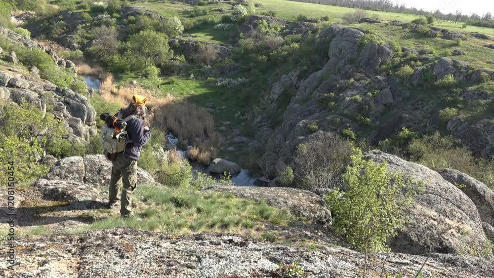 Mature Tourist man cautiously approaches edge of an abyss on mountain landscape, gorge early summer morning Mature Tourist man cautiously approaches edge of an abyss on mountain landscape, gorge early summer morning