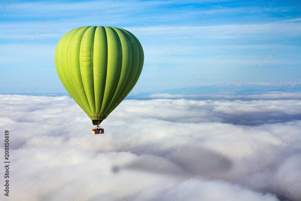 Obraz premium A lonely green hot air balloon floats above the clouds. Concept leader, success, loneliness, victory