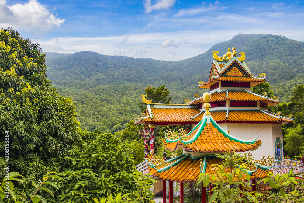Fototapeta premium Traditional Thai decorated Buddhist temple on a mountain with jungle in the foreground, Chinese Temple, Koh Phangan, Thailand