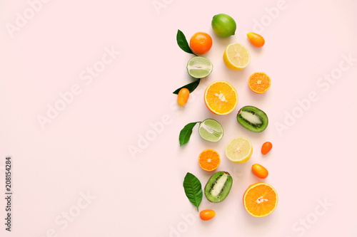 Fruit background. Colorful fresh citrus fruit on a light pastel pink background table. Orange, tangerine, lime, kiwi. Flat lay, top view, copy space 