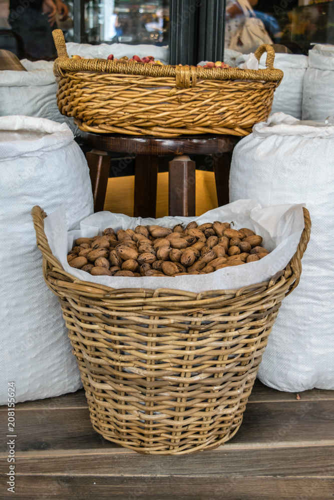 Unshelled pecans in a basket wrapped with white burlap textile, in front of the store