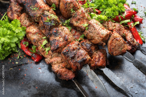 Traditional Russian shashlik on a barbecue skewer with paprika as closeup on an old board