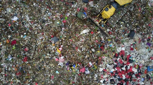 Overhead drone shot of excavator dumping trash onto garbage dump, while people scavenge through the rubbish at the Bantar Gebang landfill in Jakarta, Indonesia photo