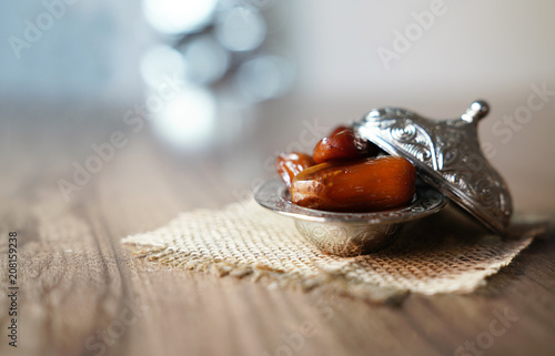 Fresh fruit dates in a silver metal bowl on a piece of sackcloth on walnut wooden table photo