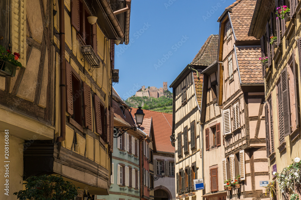 Steet in Beauville village with ruins up the hill, Alsace, France