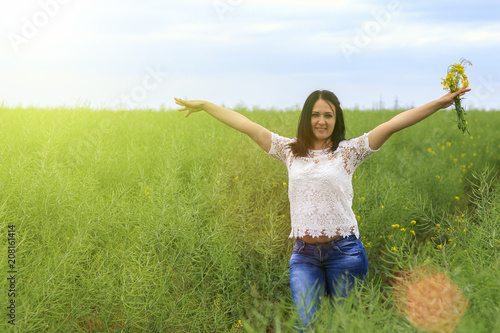 A beautiful young brunette in the field with her arms out to the sky sincerely enjoys a happy moment in life, toned photo