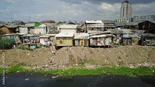 Kids throw rocks at a drone flying past slum housing and pollution, poverty in suburbs of Jakarta, Indonesia