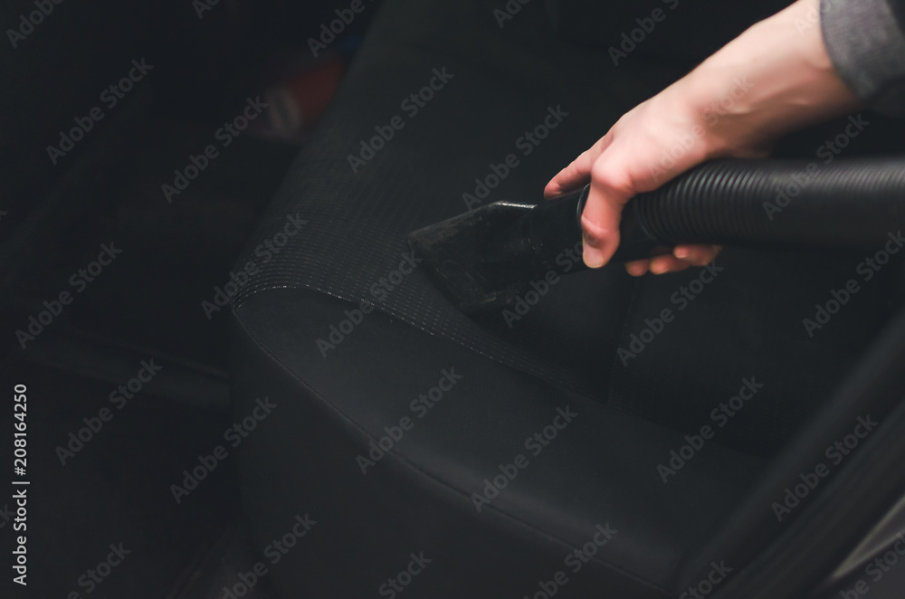 Man vacuums the seats inside a car on car wash selfservice close up