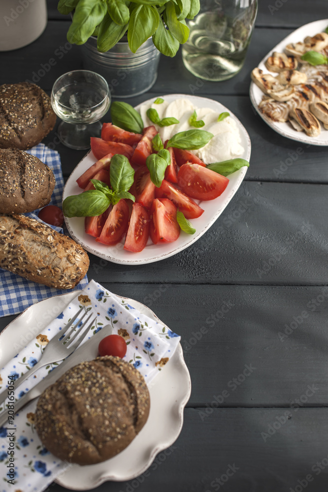 Salad with caprese, fresh basil and grain bread on a black background. Copy space, flat lay.