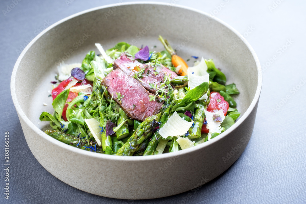 Modern spring salad with barbecue dry aged sliced fillet steak and green asparagus as top view on a plate Modern spring salad with barbecue dry aged sliced fillet steak and green asparagus as top view on a plate
