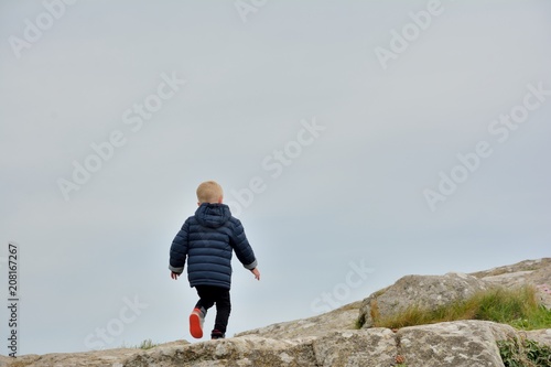Un jeune enfant fait de l'escalade dans les rochers sur la côte bretonne © aquaphoto