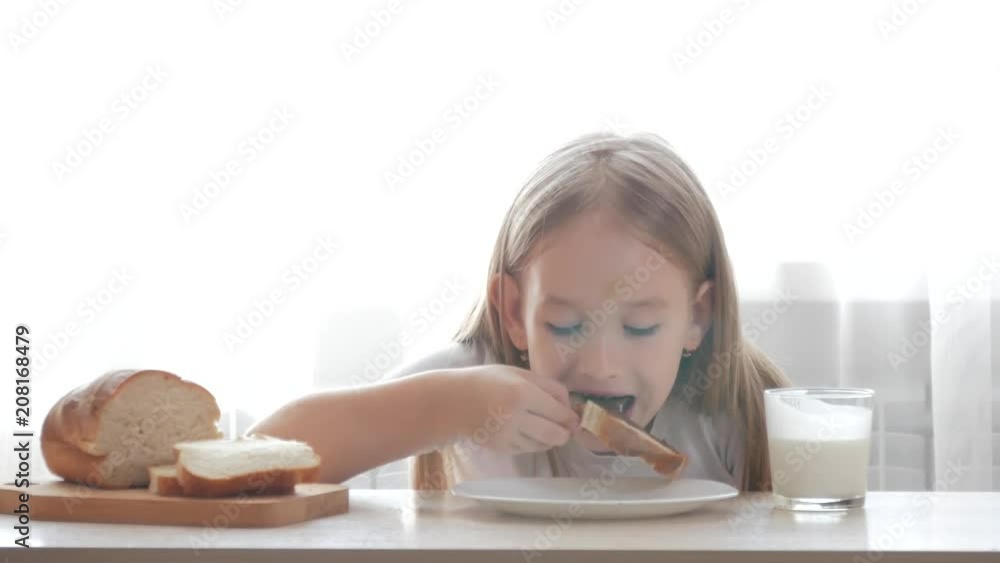 Child drinking milk and eating a sandwich. Girl holding a sandwich and she are to tasting. Child drinking milk and eating a sandwich. Girl holding a sandwich and she are to tasting.