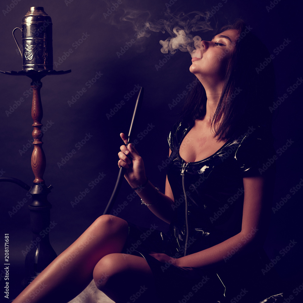 Young, beautiful girl smokes a hookah or shisha or kalian. Smoke and  passion. Leather or latex dress, sexy outfit.The pleasure of smoking. Stock  Photo | Adobe Stock