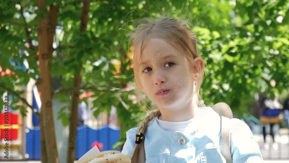 Beautiful young girl eating a hot dog in a park. Beautiful young girl eating a hot dog in a park.