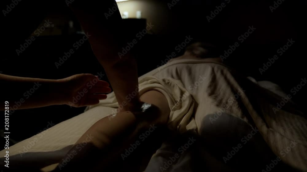 Young female getting a back and head massage with hands and hot stones Young female getting a back and head massage with hands and hot stones